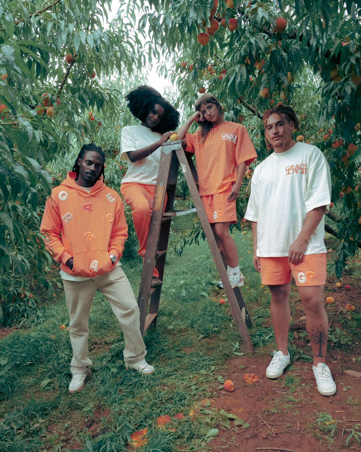 Four people in matching Peach and cream outfits standing in an orchard.