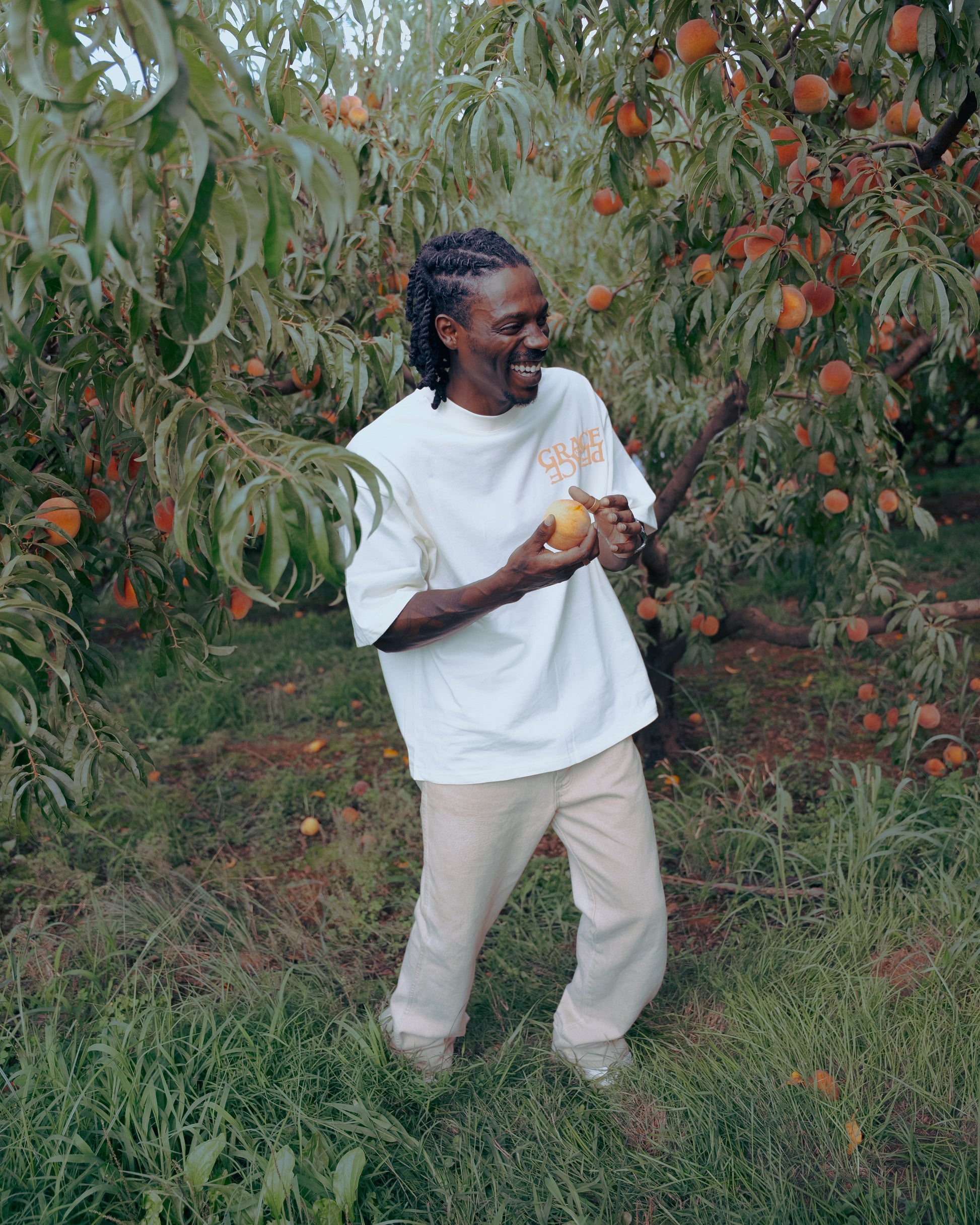 Person wearing a cream shirt with peach text in a peach orchard