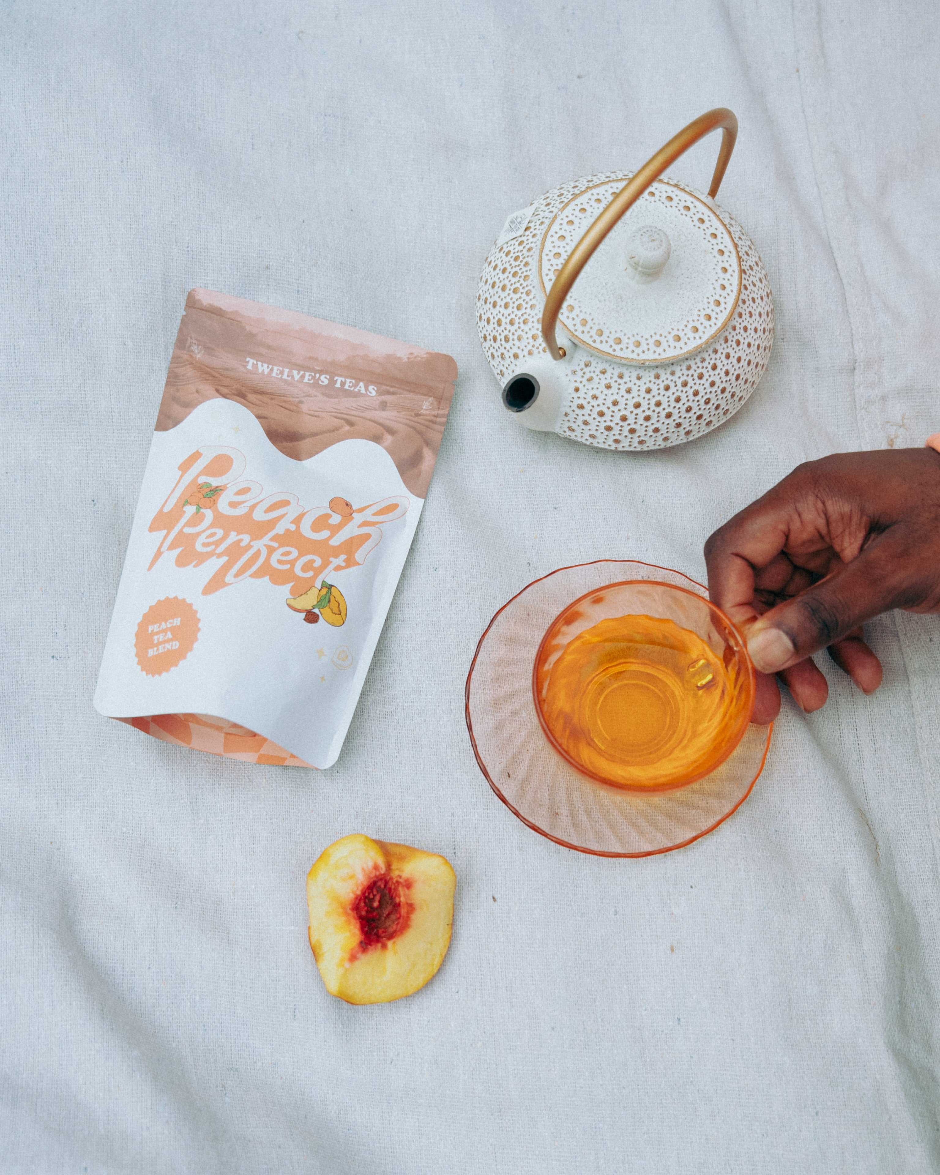 Tea bag, teacup with tea, and peach slice on a picnic blanket