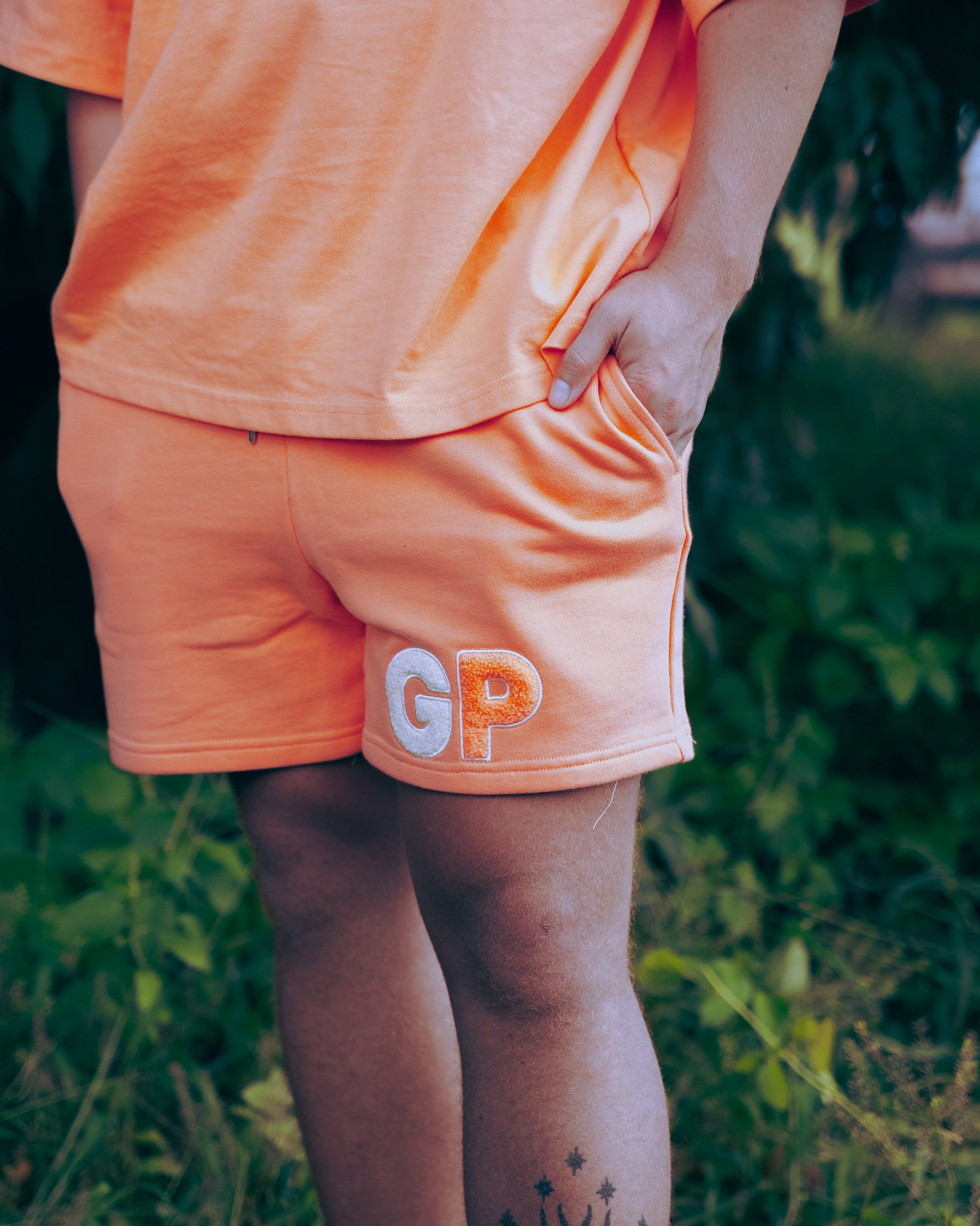 Person wearing Peach shorts with 'GP' logo outdoors