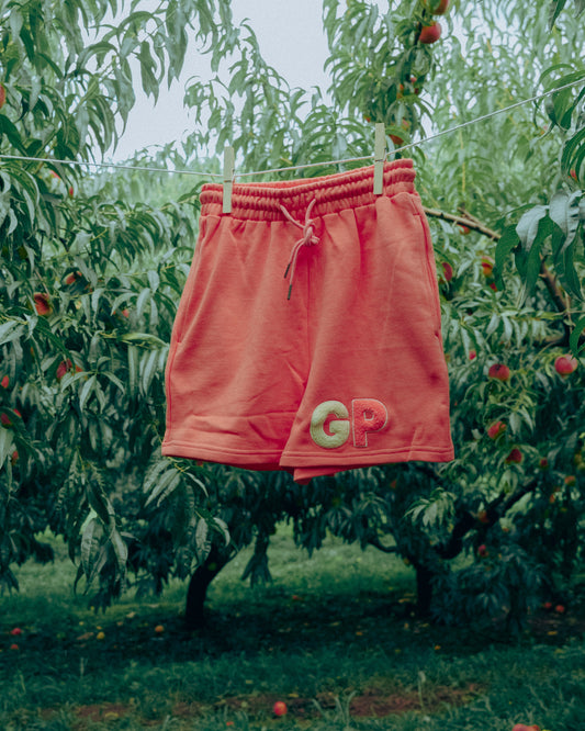 Peach shorts with 'GP' logo hanging on a clothesline in an orchard.